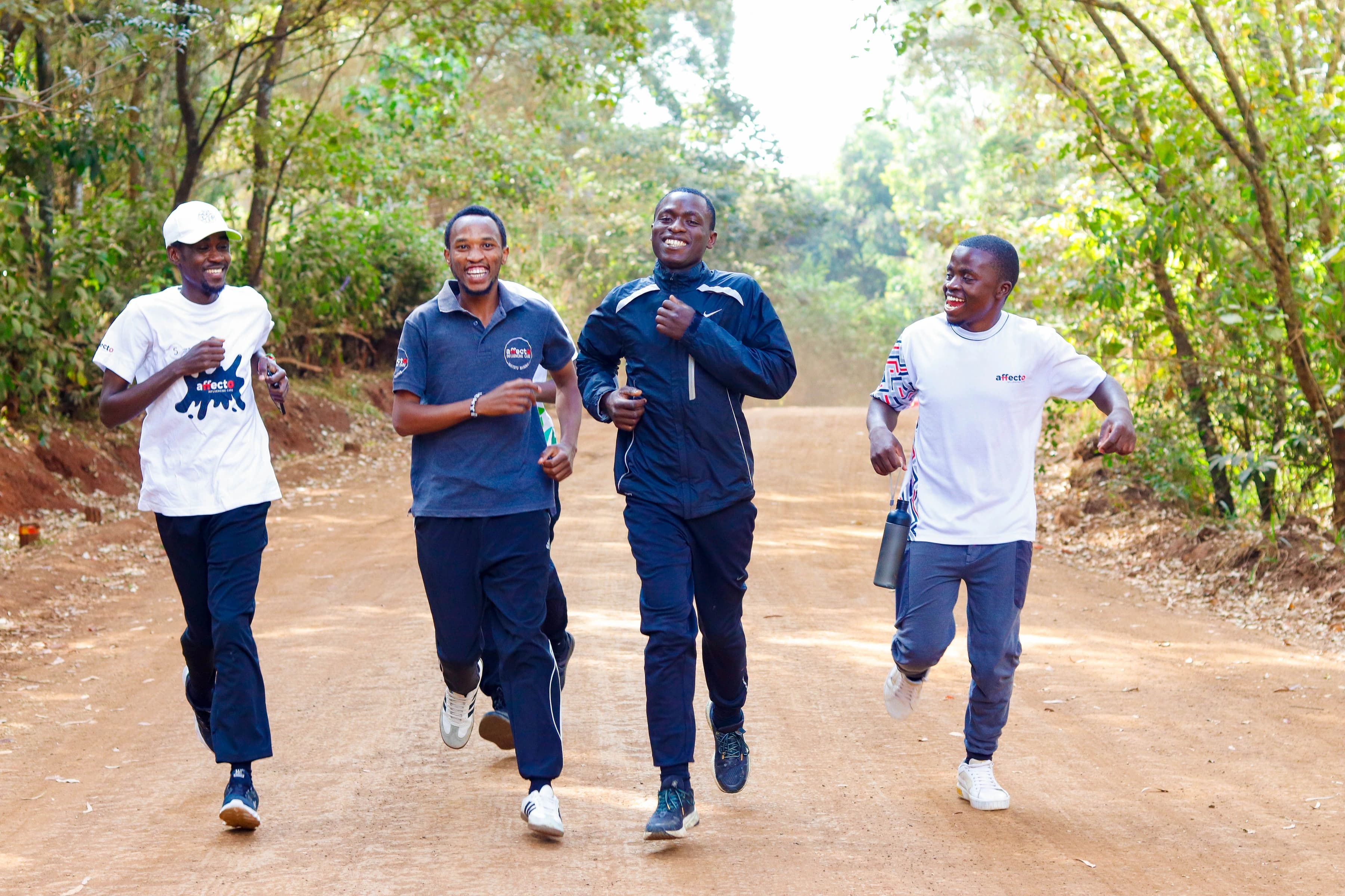 Four Affecto community members running together on a tree-lined road